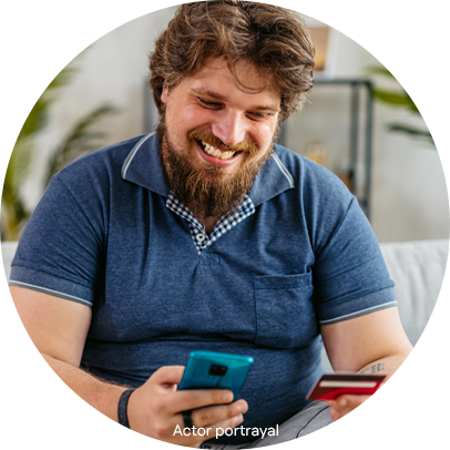 Financial Assistance Man smiling while looking at his mobile phone holding a credit card